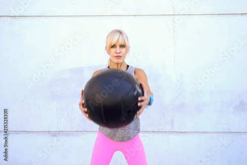 Foto Fit woman holding medicine ball at chest, standing ready for strength exercise a