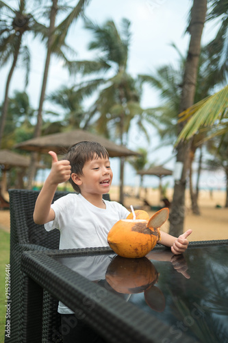 Joyful boy enjoying coconut drink at a beach resort in Sri Lanka