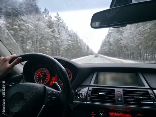 фотографія Driver traveling along a snowy forest road viewed from inside a car