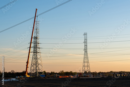 Crane Erecting Steel Transmission Tower Near Power Lines
