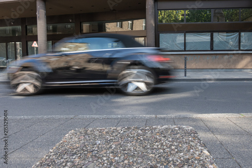 Canvastavla Car drives quickly down a city street while passing by closed shops and empty sp