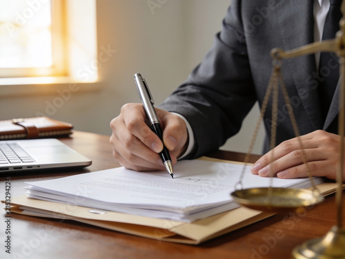 High-resolution professional stock photo of a lawyer signing official legal documents with a fountain pen on a wooden desk.