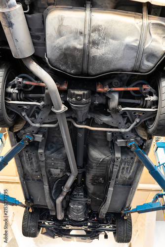 Full directly underneath view showing the chassis, drivetrain, exhaust system, and suspension of a car raised on a hydraulic lift.