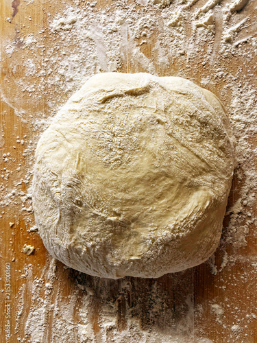фотографія Homemade yeast dough ball for pies on a floured wooden surface, fresh raw pastry