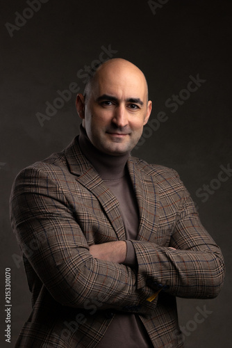 Smiling middle aged man in patterned blazer jacket and turtleneck sweater in studio portrait