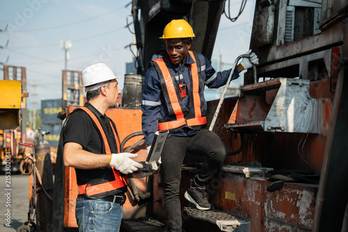 Картината върху платно Two logistics technicians discuss heavy reach stacker maintenance plan using lap