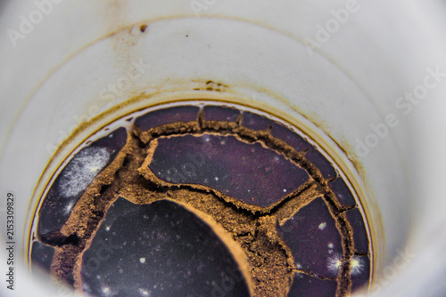 Rotten spoiled dry cracked coffee grounds remaining at the bottom of the cup, brown red, beige, green mold spots, leftover for many days in a white mug, macro closeup shot, Cairo Egypt