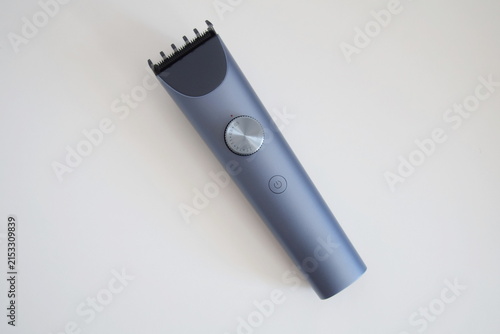 Modern wireless hair clipper with short comb attachment on white background