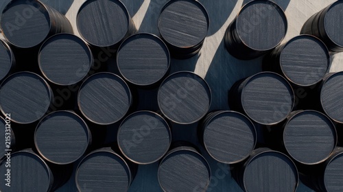 Aerial view of neatly arranged dark barrels casting shadows on a smooth surface