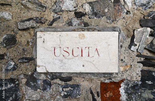 Foto Ancient stone exit sign with Italian text Uscita carved on a historic rustic roc