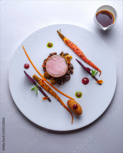 Konstfotografi Tender pork medallion served with glazed carrots, vegetables and refined sauce on a white plate, creating a sophisticated gourmet presentation for modern fine dining concepts