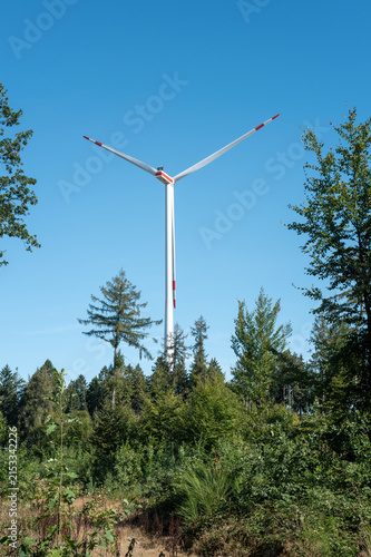 Wind turbine standing tall in a forest on a clear day