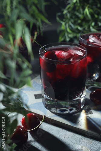 Glasses with cold cherry drink with ice in low key