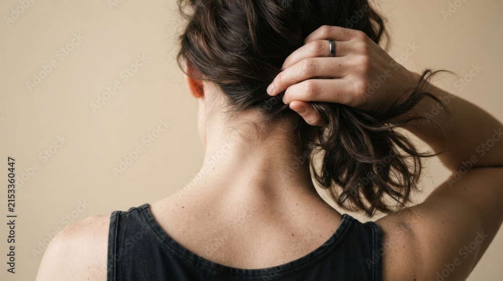 Fototapeta premium Woman Styling Hair with Hand Against Neutral Background