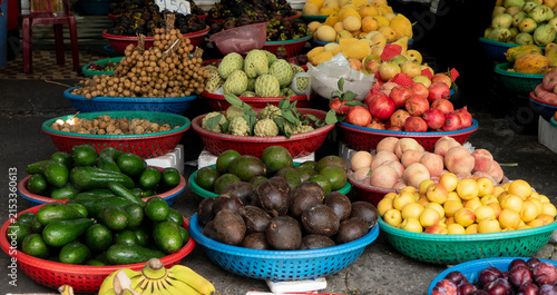 Konstfotografi Colorful baskets of avocados, pomegranates, longan, custard apples and other fresh fruits at a traditional Vietnamese market