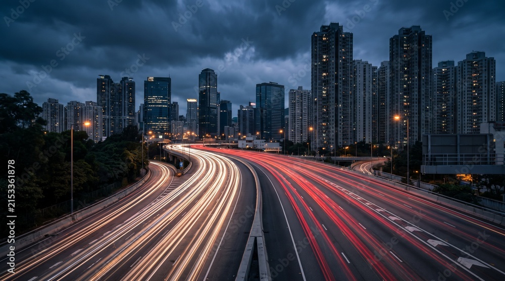 Fototapeta premium Urban Highway Interchange at Twilight with Long Exposure Traffic Light Trails and Modern City Skyline