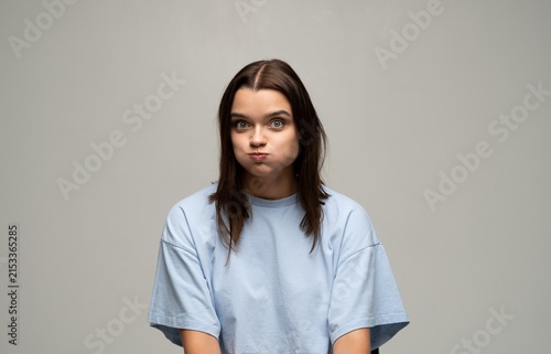 Fotografie Young woman puffing cheeks and holding breath with wide eyes, making a playful s