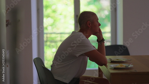Obraz na płótnie Woman undergoing cancer treatment sitting alone at dining table at home, quietly