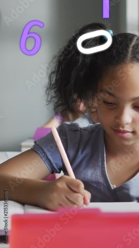 Animation of numbers over happy schoolgirl writing at desk in class