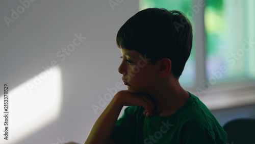 Fotografie Pensive thoughtful young boy resting chin on hand at home, deeply contemplating
