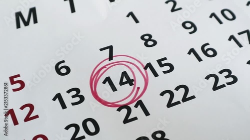 A close up view of a calendar page with the fourteenth day circled in red ink.