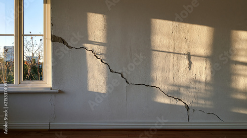 Large diagonal crack on a white interior wall near a window. Symbolic image for home inspection and structural damage.