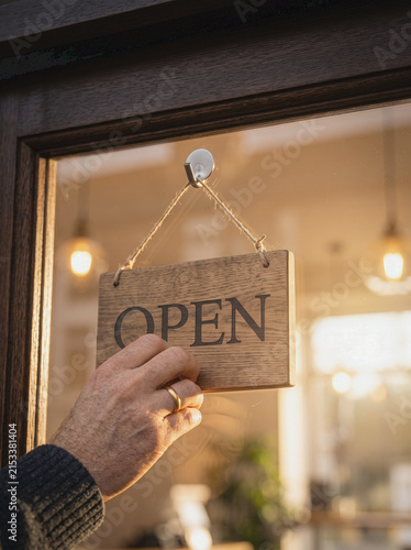 Hand Flipping Open Sign on Small Business Glass Door