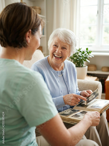 Smiling older woman pointing at a photo album while seated with a younger woman