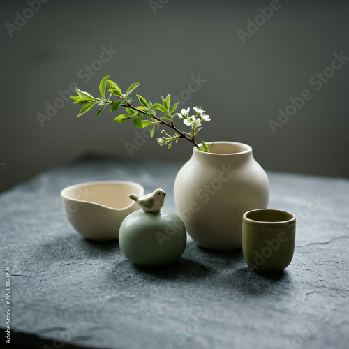 Ceramic bowl bird pot floral vase and cup arranged on dark slate surface