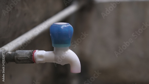 Blue and White Plastic Water Tap Connected to Metal Pipe