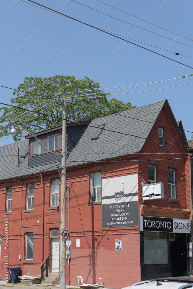 Fototapeta premium wide view of historic house and signage outside Toronto Signs, a sign shop, located at 302 Broadview Av