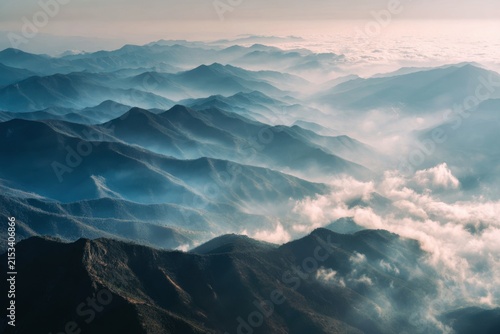 Mountain peaks rising through flowing morning fog