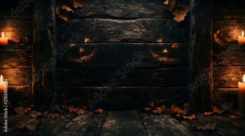 Dark and moody halloween background with autumn leaves and glowing candlelight