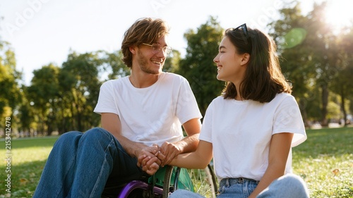 Happy young woman and man with disability shaking hands showing support outdoors connection