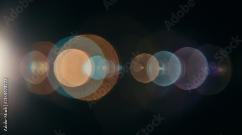 Abstract cinematic lens reflection with several soft translucent circular light artifacts, subtle cyan and amber reflections, atmospheric glow, delicate optical imperfections, dark black background