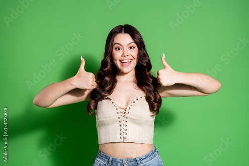 Foto Happy young woman giving two thumbs up with a cheerful smile against a bright gr