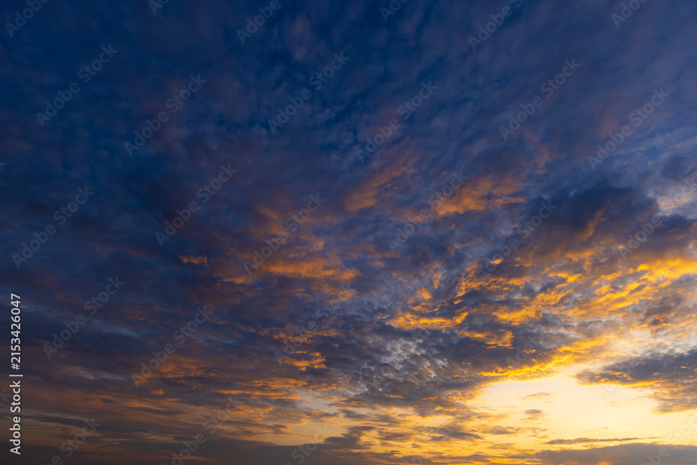 Fototapeta premium Stunning Sunset Sky with Colorful Clouds and Golden Horizon,A breathtaking view of a vibrant sunset sky filled with dramatic golden, orange, and pink clouds scattered across a serene blue atmosphere,