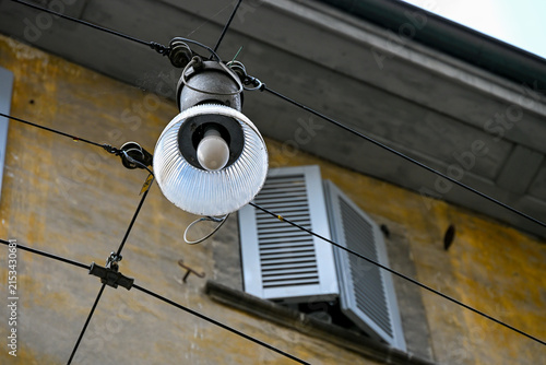 Vintage street lamp and shutters on weathered facade in Bergamo, Italy