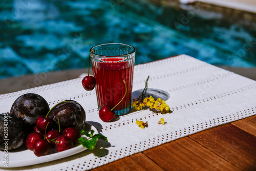 Refreshing organic fruit drink with fresh cherries and plums on poolside terrace