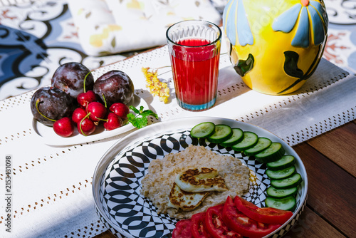 Oatmeal with cucumber, tomato and grilled halloumi cheese served on modern ceramic plate on terrace by pool