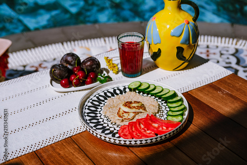 Oatmeal with cucumber, tomato and grilled halloumi cheese served on modern ceramic plate on terrace by pool