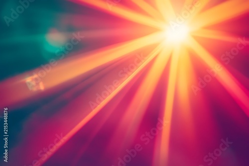 Bright yellow sunburst light rays on a magenta and teal background with bokeh with illumination celebration explosion spotlight