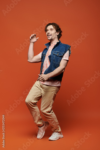 фотографія Handsome man in stylish attire expressing vibrant emotions against a warm backdr