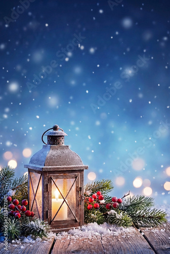 Rustic lantern glowing with winter decorations on a snowy surface  