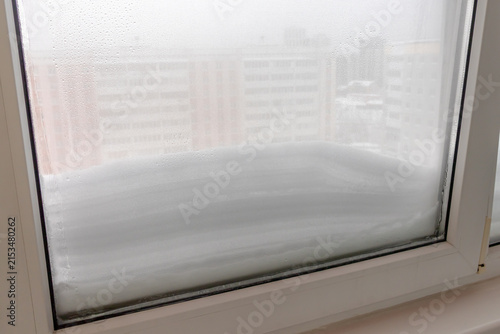 In winter, snow lies outside the window of a high‑rise building. A snowdrift has formed outside the window after a heavy snowfall. Heavy snowfalls in the middle of winter.