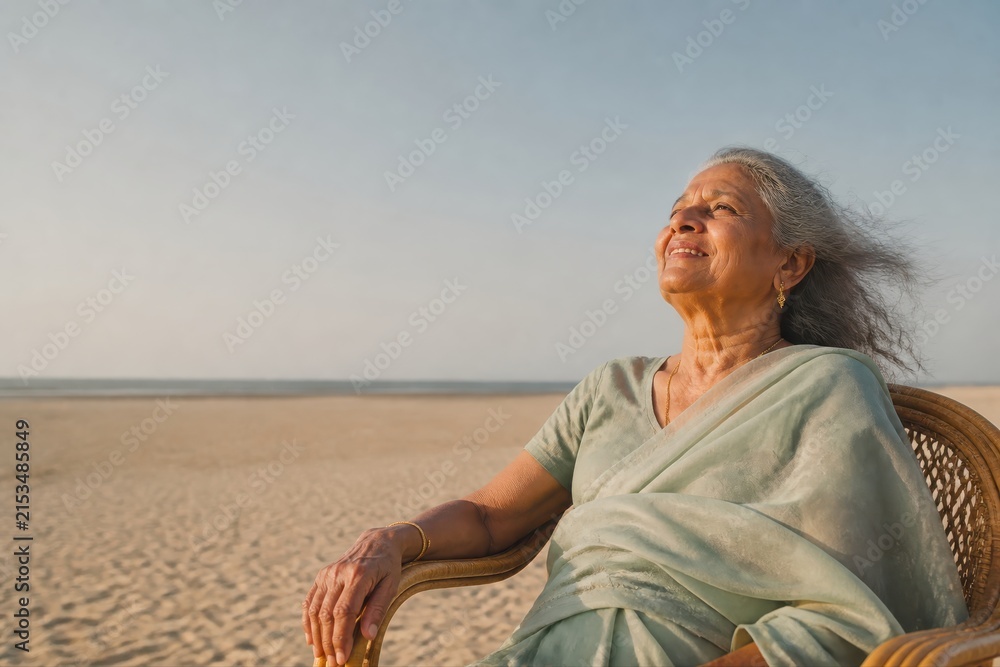 Fototapeta premium Senior woman relaxing on a peaceful beach with open sky and sea