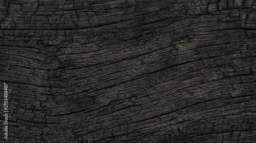 Close-up of weathered dark textured wooden surface showing intricate grain patterns and natural cracks for abstract design use