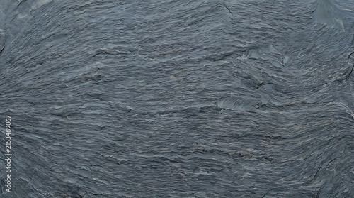 Close-up shot of textured dark gray stone surface with intricate natural patterns and rough uneven details for artistic or