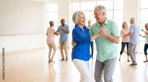 Happy senior couple dancing together during active aging fitness class at community center