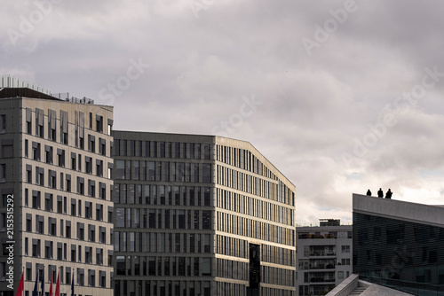 Across Oslo, Norway, clouds settle over a modern office skyline, where urban architecture and a measured facade define the restrained cityscape.